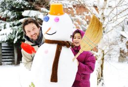 girl enjoying winter with snowman
